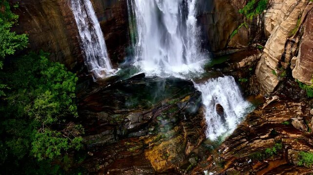 Drone aerial landscape of flowing Ravana waterfall surrounded by rocky terrain trees in forest in nature wilderness in Ella Sri Lanka Asia landmark attraction travel tourism holidays