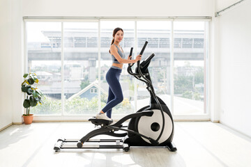 Woman exercising on an elliptical trainer in a bright home gym. Perfect for concepts like cardio, weight loss, fitness routine, healthy lifestyle, indoor workout, personal training, and home exercise.