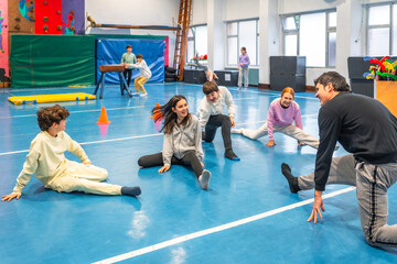Students stretching with teacher in school gym class