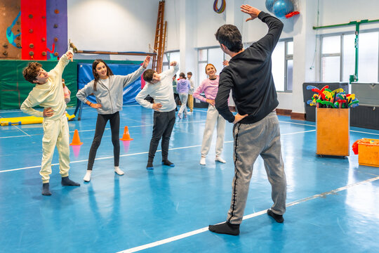 Group of students stretching with teacher in school gym - Powered by Adobe