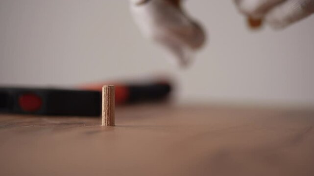 Furniture assembler removing wooden dowel with pliers from furniture piece while assembling