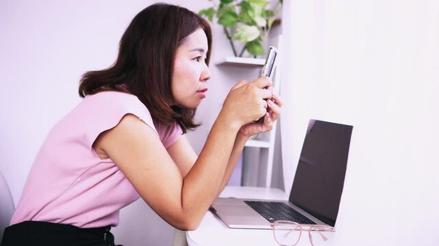 Asian woman with incorrect posture, hunched back, and forward head while using a mobile phone, suffering from back pain, kyphosis, and eyestrain
