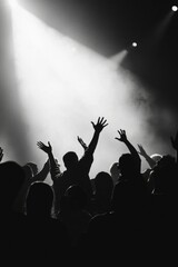 Concert audience cheering at dark stage bathed in light, entertainment