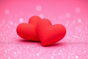 Obraz premium Pink glittery bg two red hearts facing each other small white dots bokeh