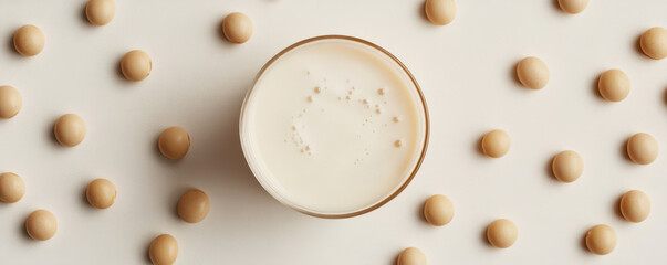 Artistic flat lay of soy milk in frosted glass surrounded by soybeans, creating serene and minimalist aesthetic. Perfect for health and wellness themes