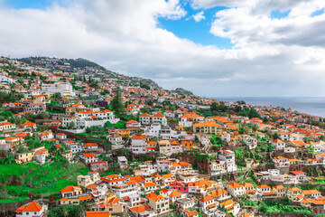 Fototapeta premium Panoramic view of Funchal, the capital city of Madeira, Portugal with unique and picturesque architecture. Densely packed buildings with tiled roofs, which are spread across the hilly terrain