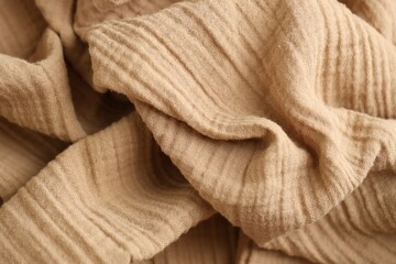 Texture of crumpled linen fabric under natural light in peach fuzz color