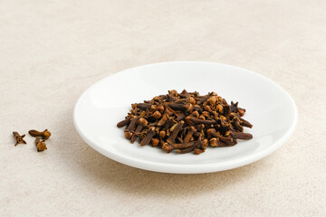 Dried cloves or cengkeh, dried herbs served on white plate
