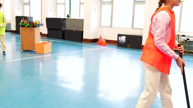 Elementary school students enjoying a game of floorball during gym class, showcasing teamwork and sportsmanship