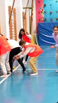 Elementary school students learning and playing floorball in gym class, developing teamwork and hand eye coordination