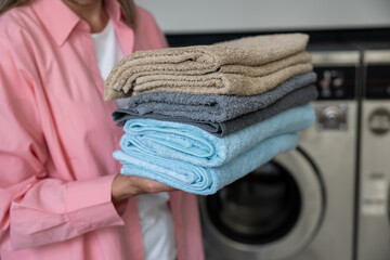 Contented mature caucasian woman holding a pile of clean clothes