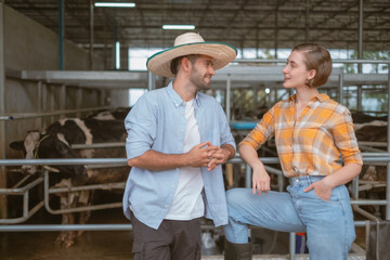 Portrait of Young Latin man and White woman standing beside stable of cow farm looking each other and smile, Cowboy and cowgirl in dairy product or cattle beef in plant.