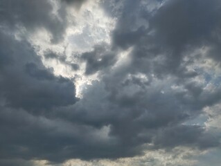 Obraz premium Dramatic dark clouds with sun shining behind. Natural texture background 