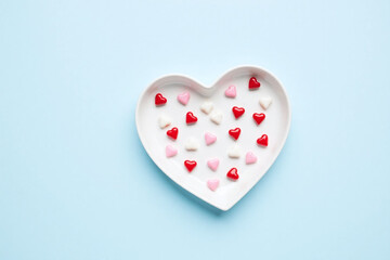 white heart shaped plate red white candies light blue background