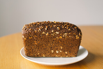 Sourdough bread, freshly baked and still warm, are stacked on a wooden surface. The bread are covered in seeds sesame and sunflower, adding a rustic and flavorful touch.