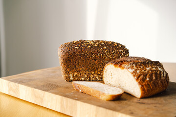 Sourdough bread, freshly baked and still warm, are stacked on a wooden surface. The bread are covered in seeds sesame and sunflower, adding a rustic and flavorful touch.