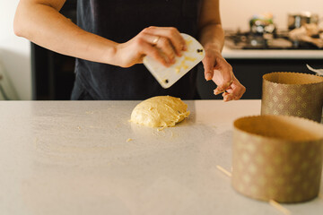 A woman in casual attire prepares dough for baking. She looks pleased and focused, enjoying the baking process in a light-filled kitchen.