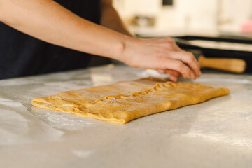 A woman in casual attire prepares dough for baking. She looks pleased and focused, enjoying the baking process in a light-filled kitchen.