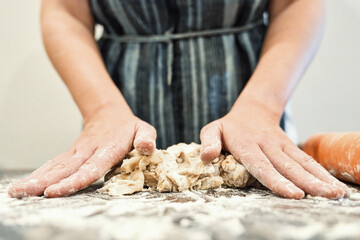 Hands young woman mixing fresh dough on wooden table while making homemade baking in kitchen.. Homemade baking concept