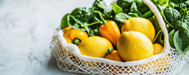 Fresh lemons and yellow peppers in white mesh bag with spinach, showcasing vibrant colors and healthy produce. Perfect for nutritious meal or snack