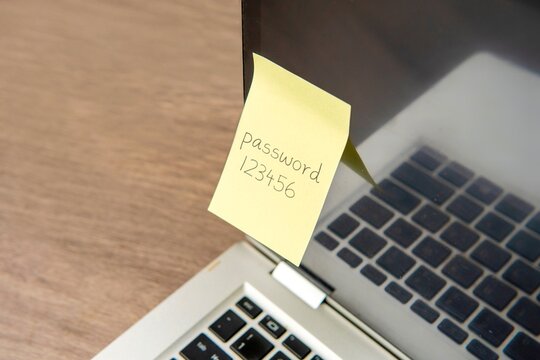 Sticky note with the word "password 123456" on a laptop keyboard. Data protection, password strength concept.