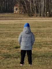 Chłopiec na łące na tle lasu i starego drewnianego domu © tomo81