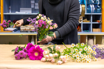 Florist arranging bouquet with fresh flowers in workshop