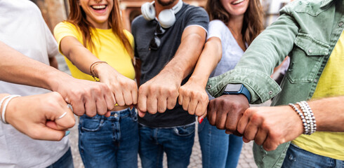 Multi ethnic group of young people making fist bump as symbol of unity, community and solidarity -...