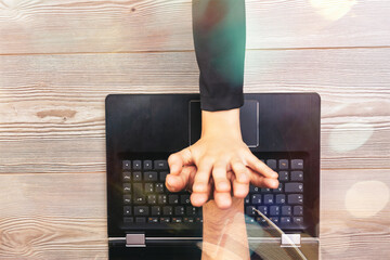 Businesspeople joining hands over laptop keyboard