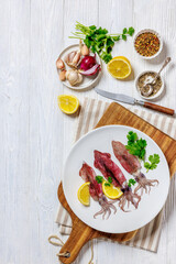 Whole fresh raw baby squid on a white plate