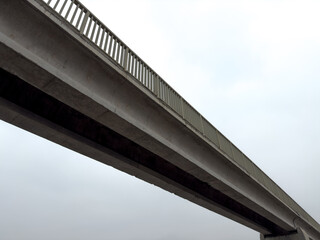 Concrete pedestrian bridge against gray sky
