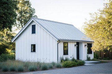 Obraz premium This charming modern white cottage, nestled among lush greenery, features a stylish metal roof and is perfectly situated in a tranquil environment that shines beautifully during daylight hours