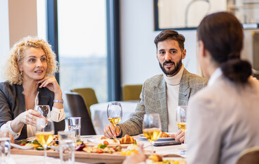 Portrait of businessman sitting with coworkers in restaurant, talking during business lunch.