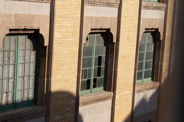 Arched windows in a brick wall, light and shadows playing on the facade. Architectural details,...