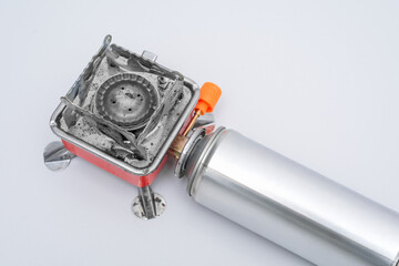 Portable gas stove for camping with a cylinder on a white background. Replaceable gas cylinder and...