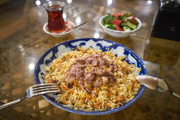 Tashkent plov on the table with tea and salad