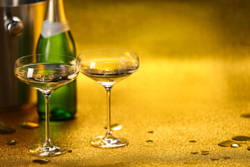 Champagne in glasses, bottle and ice bucket on golden background. Space for text