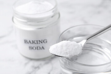 Glass of water and baking soda on white marble table, selective focus
