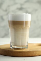 Tasty latte macchiato in glass on white wooden table, closeup