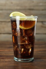 Refreshing iced cola with lemon slices on wooden table, closeup