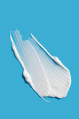 A sample of white cosmetic moisturizer on a blue background