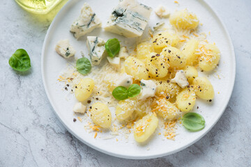 Italian gnocchi served with blue cheese and basil on a white plate, horizontal shot, middle close-up