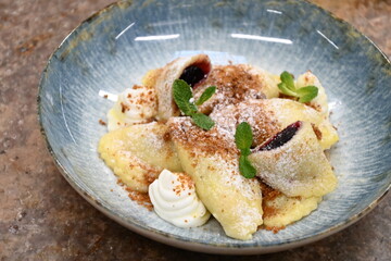traditional european sweet dish varieniki pastries with blueberries, sweet lunch served food on a plate in a restaurant