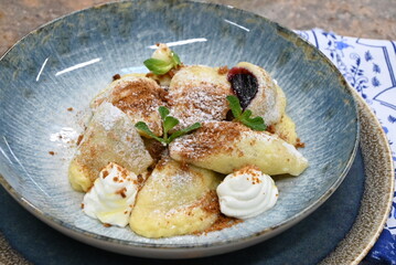 traditional european sweet dish varieniki pastries with blueberries, sweet lunch served food on a plate in a restaurant