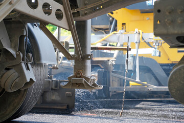 Low Angle Close-up of Truck Trailer with Asphalt Paver in Background