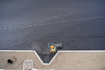 Aerial View of Construction Worker Finalizing Asphalt Around Drainage Grate