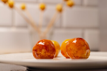 Coconut balls coated in glass icing sugar on a white plate, traditional Brazilian Bala Baiana dessert.
