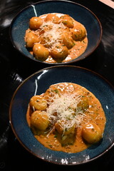close up view of food background, potato gnocchi with pepper cream sauce, grated parmesan cheese and herbs, close up view of served food