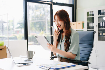 Asian business woman are delighted and happy with the work they do on their tablet, laptop and...