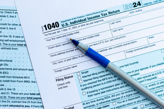 Close-up shot of a blank color print 2024 Form 1040 U.S. Individual Income Tax Return. With a blue ball pen. 2025 Tax season, taxation, tax payment and regulatory filing concept